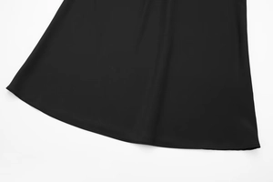 Close-up of black satin midi skirt hem showing high-quality stitching and drape