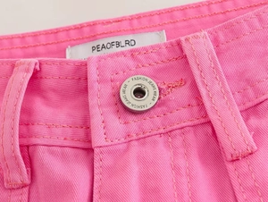 Close-up of pink straight-leg cargo pants featuring denim waist details and metal button