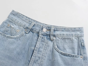 Detail of high-waisted denim shorts featuring vintage light blue wash and metal button closure