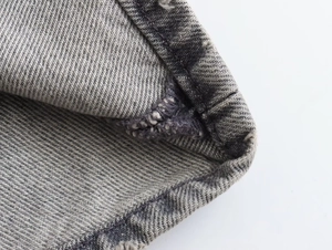 Close-up detail of dark grey washed denim fabric with precise stitching and twill texture