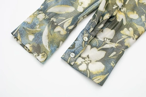 Détail des poignets à double boutonnage avec imprimé floral bleu sur tissu tissé