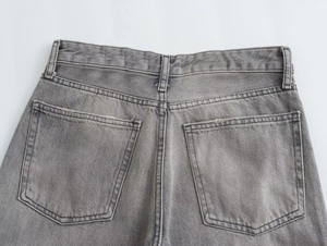 Detail of the back waist, pockets, and washed gray texture of these wide-leg denim jeans