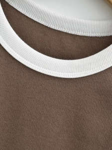 Detail of the white contrast crew neck on a dark brown ribbed knit cropped tank top