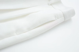 Detailed view of waistband and side pocket stitching on white wide-leg trousers