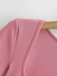 Close-up of pink ribbed knit texture and square neckline on a wooden hanger