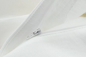 Detail of the hidden white nylon zipper on high-quality white fabric with neat stitching