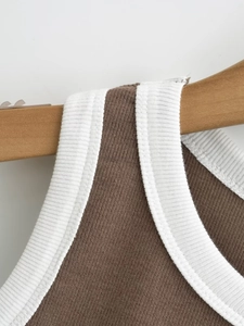 Detail view of brown ribbed knit tank top with white contrast edging on wood hanger