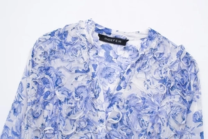 Detail of blue and white floral chiffon top with layered ruffles and brand neck label