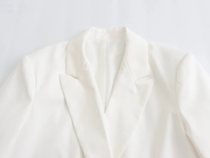 Detailed view of the elegant notched lapel and woven texture on a white blazer for women
