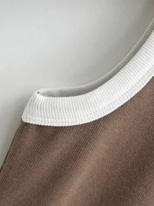 Close-up of ribbed knit texture on a contrast brown and white crew neck vest top