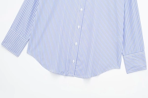 Detail of blue and white striped poplin shirt showing white buttons and curved hemline