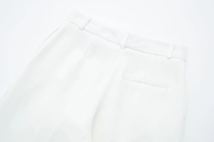Close-up of white high-waisted trousers with belt loops and a back welt pocket detail