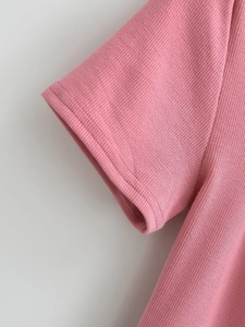 Detailed macro view of pink ribbed knit fabric and sleeve stitching on the summer T-shirt