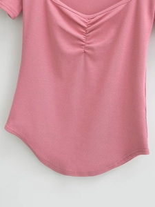 Detailed view of pink ribbed knit fabric with ruched U-neckline and tight stitching