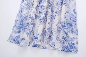 Detail of white chiffon dress fabric with blue floral print and pleated draped hemline