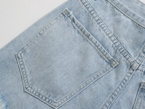 Close-up of light blue denim shorts back pocket with distressed details and stitching