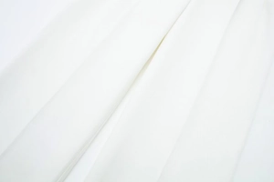 Macro shot of the white pleated fabric showing detailed vertical texture and twill weave