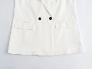 Detail showing double-breasted black buttons and flap pockets on white blazer