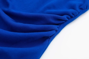 Detail of royal blue ribbed knit dress showing intricate ruched side seam design