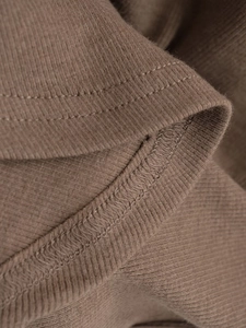 Close-up of brown ribbed knit fabric showing detailed stitching and soft texture