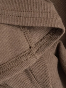 Dettaglio ravvicinato del tessuto in maglia a coste color terra con cuciture curate