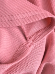 Detail of pink ribbed knit fabric showing high-quality double-needle stitching and seams