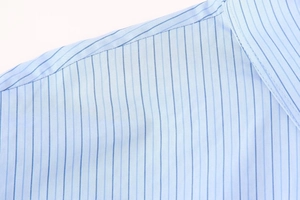 Detailaufnahme der Schulternaht und blauen Streifen auf hellem Popeline-Hemdenstoff