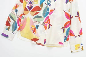Close-up of colorful abstract floral print on cream-colored poplin shirt with buttons