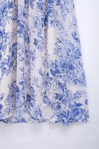 Close-up of lightweight white fabric with elegant blue floral print and fine hem details