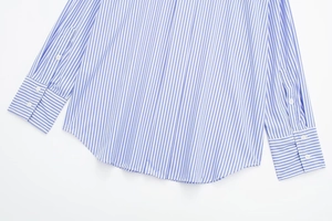 Detail view of blue and white striped shirt with round hem and buttoned cuffs