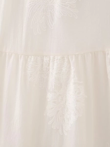 Detailed macro shot of white jacquard satin fabric with elegant floral daisy embroidery