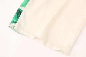 Détail du tissu crème fluide avec imprimé vert et finitions de couture d'ourlet nettes