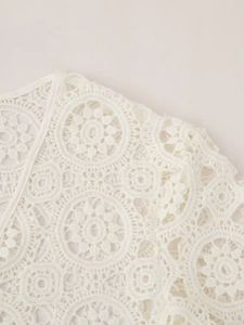 Macro detail of white crochet lace dress featuring intricate floral hollow patterns