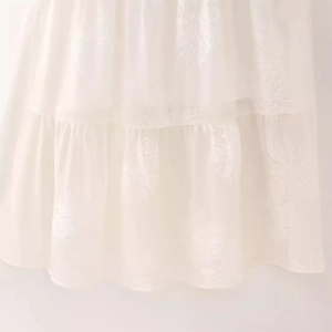 White halter neck dress with floral embroidery and layered ruffle details