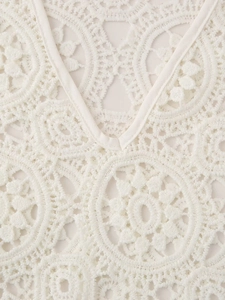Macro view of white V-neck lace dress with intricate round cutout embroidery patterns