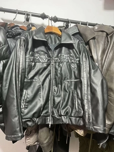 Détail d'une veste en similicuir noir avec nœud brodé et rayures gris argenté