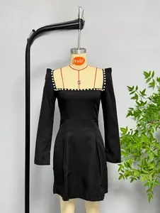 Close-up of elegant square neck black mini dress with white pearl trim along the neckline