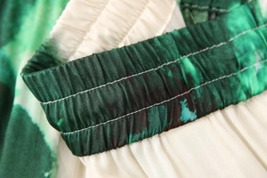 Détail de la taille élastique avec coutures et tissu plissé à motif tie-dye vert et blanc