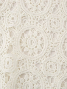 Detailed close-up of white floral lace embroidery with intricate hollow-out patterns