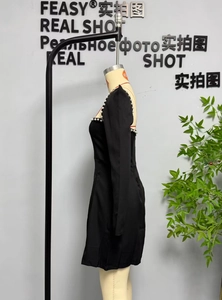 Close-up of elegant square neckline and delicate white pearl trim on a black dress