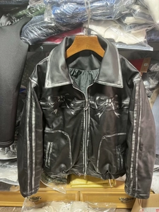 Détails d'une veste vintage en cuir noir avec nœuds argentés et bords gris effet vieilli
