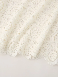 Detail of elegant white floral lace fabric with intricate hollow embroidery and scalloped edge