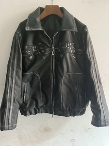 Détail du blouson noir en cuir avec nœuds embossés, bandes et ourlet élastique