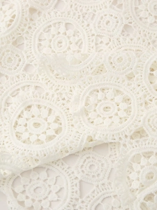 Detailed macro view of white floral lace fabric with intricate hollow-out crochet texture
