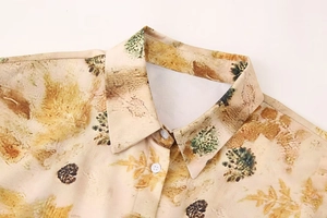 Close-up of lapel collar and pine cone print on beige summer shirt with white buttons