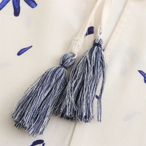 Close-up of floral print linen fabric featuring elegant blue tassels and neck drawstrings