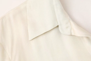Détail du col à revers et de l'épaule d'une chemise imprimée soyeuse de couleur crème