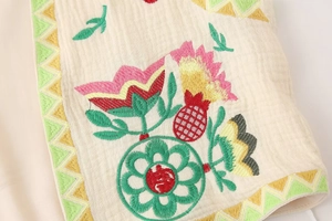 Close-up of ethnic floral embroidery on beige cotton-linen vintage sleeveless vest jacket