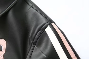 Détail d'une veste en cuir noir avec écusson de dessin animé rose et rayures