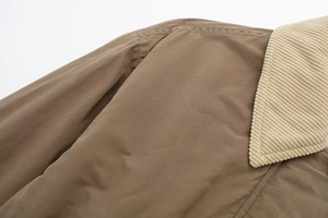 Close-up of brown twill jacket featuring a beige corduroy collar and fine stitching